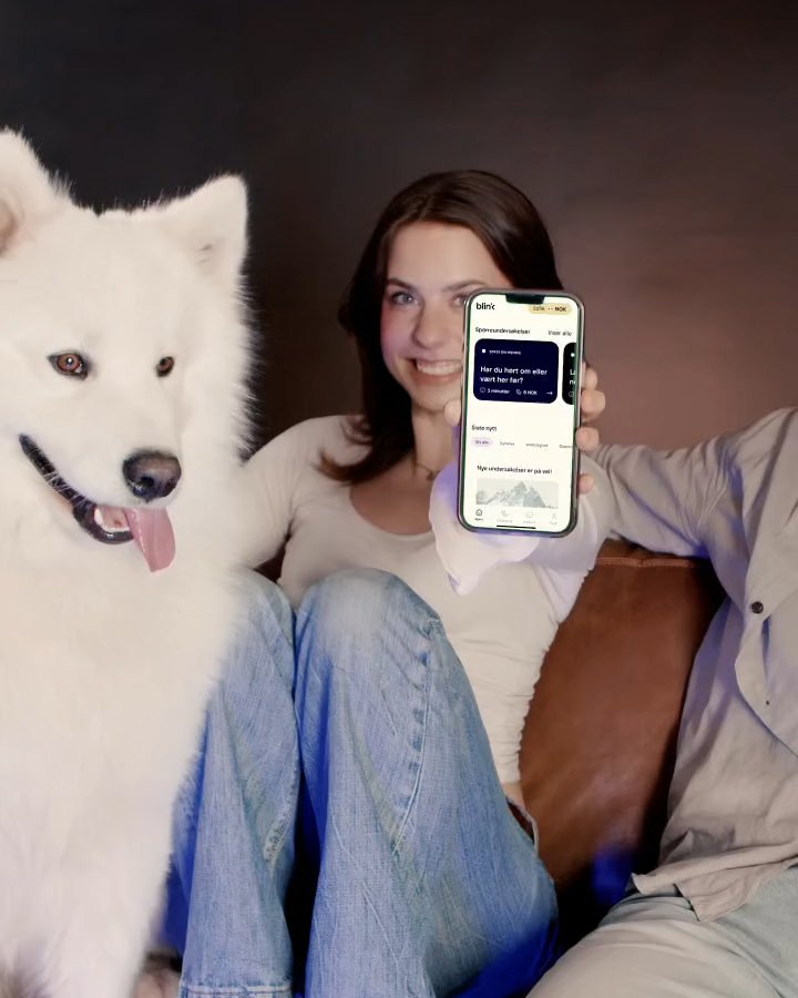 Ung kvinne med hund viser Blink Panel-appen på mobilen